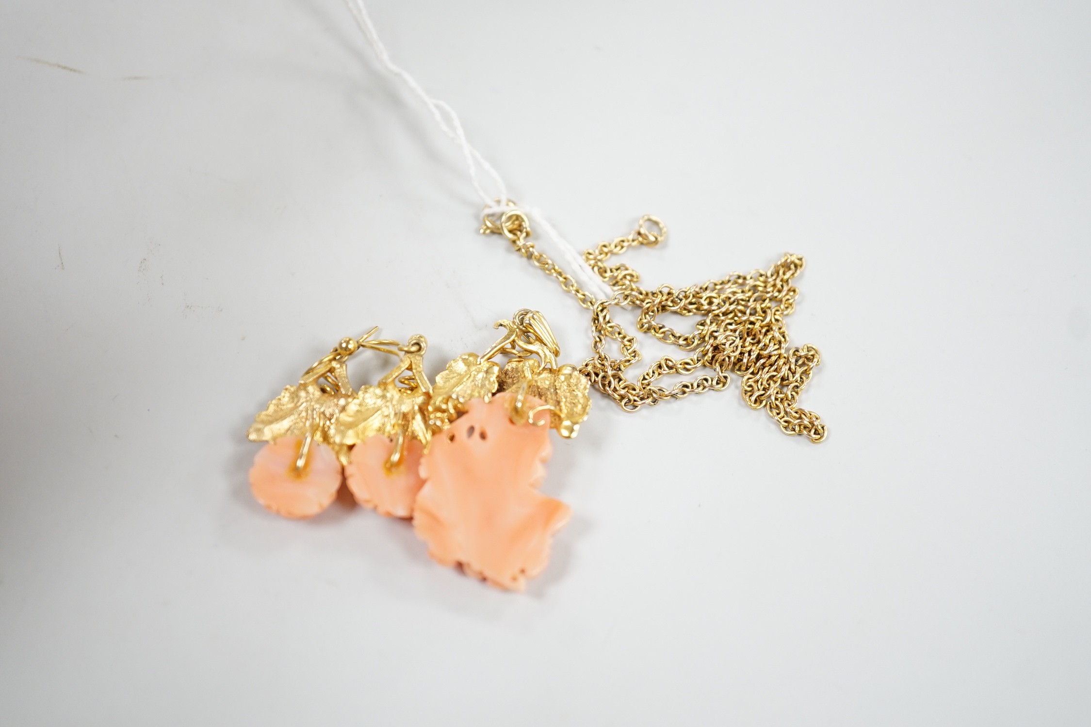 A modern suite of yellow metal and carved coral jewellery, comprising a pendant , 40mm, on chain, 45cm and a pair of matching drop earrings stamped 9ct gold, 26mm, gross 15.2 grams.